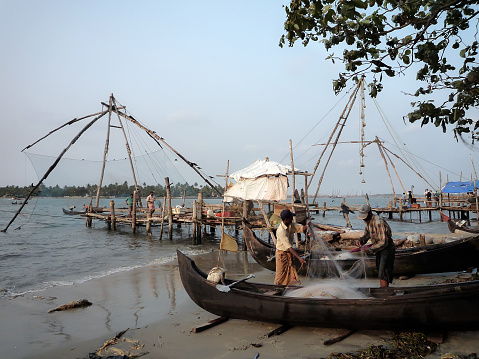 India, Kerala, Cochin: two fishermen fix their fishing nets at the end of the day