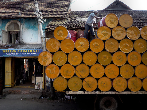 India, Kerala, Cochin: a man removes yellow bins from his truck