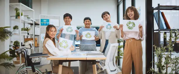 Photo of Group portrait of young millennial generation Z business people hold recycle symbol with smile. Net zero, waste recycling campaign, carbon neutrality global warming, environmental conservation concept