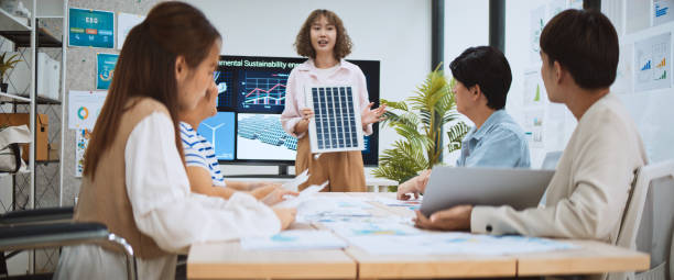 asian business people team brainstorm meeting in sustainable corporate office. presentation esg project planning, solar panel, wind turbine power energy generation. environmental conservation concept - animação digital - fotografias e filmes do acervo