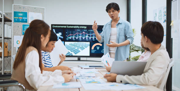 asian business people team brainstorm meeting in sustainable corporate office. presentation esg project planning, solar panel, wind turbine power energy generation. environmental conservation concept - animation fotografías e imágenes de stock