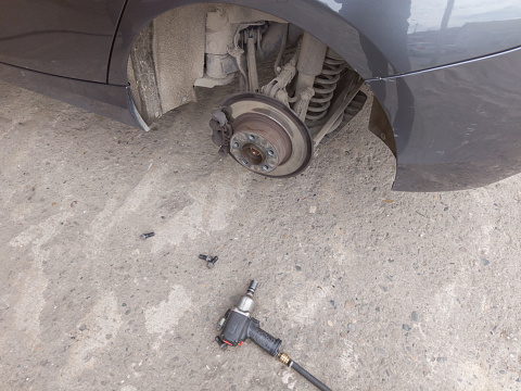 Wheel removed from car so brake disc and pads can be visually inspected in auto repair shop