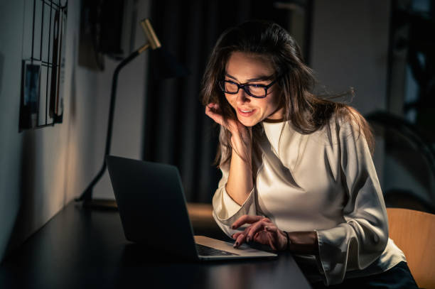 istock Woman using laptop for remote working at home at night in dark room 2053405303