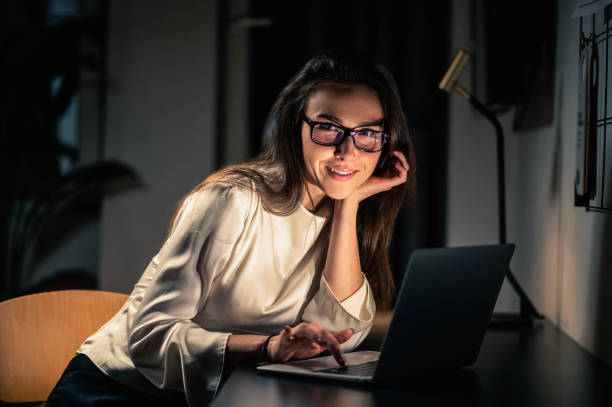 istock Woman using laptop for remote working at home at night in dark room 2053405822