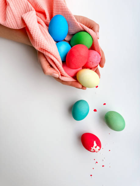 istock Hands holding colorful painted Easter eggs with one cracked egg on the side, representing Easter festivities, spring celebrations, and family fun activities. 2053408565