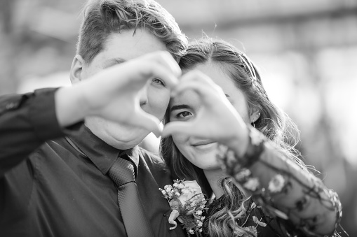 Young man and multiracial Chinese Caucasian young woman with hands making a heart shape. Black and White