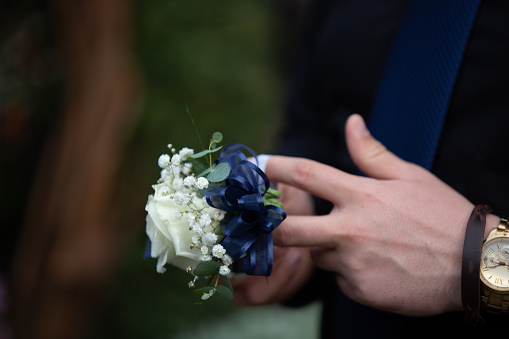 Young man prepares corsage for his date to prom