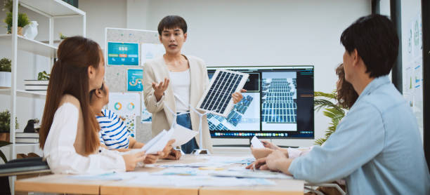 asian business people team brainstorm meeting in sustainable corporate office. presentation esg project planning, solar panel, wind turbine power energy generation. environmental conservation concept - animação digital - fotografias e filmes do acervo