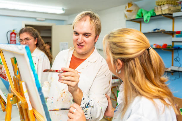 istock Disabled man painting next to a teacher in a class 2053437897