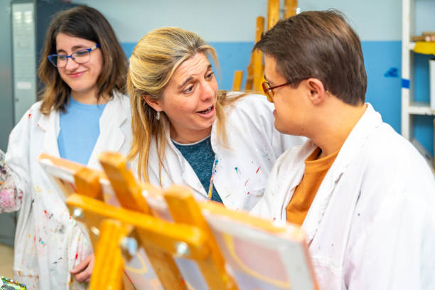 istock Art teacher talking to man with down syndrome while painting 2053442050