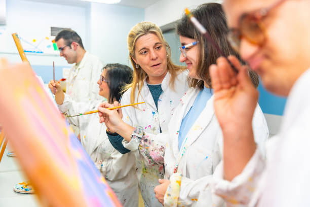 istock Instructor talking to a disabled woman painting on canvas 2053442559