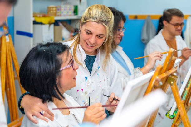 istock Teacher encouraging a disabled woman during painting class 2053443097