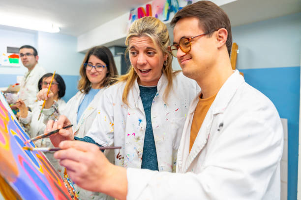 istock Instructor helping a man with down syndrome to paint 2053445172