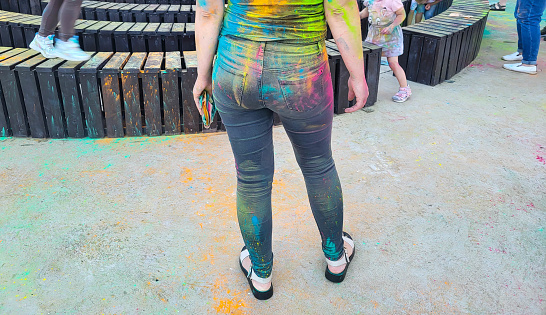 After the Holi celebration, paints were scattered on the asphalt, holi paints on the girl's back