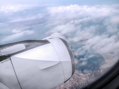 View from an airplane window of a white turbine among the clouds above a city somewhere in Turkey. View from the porthole to a cloudscape