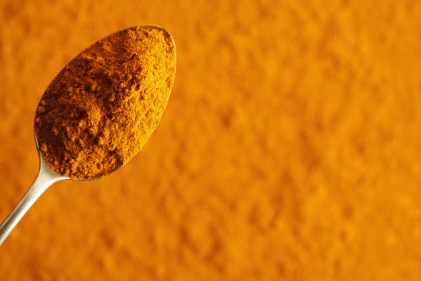 istock Turmeric root powder on a spoon on orange background with copy space 2053535932