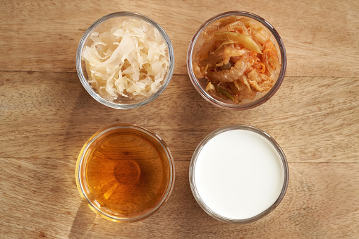 Fermented foods in glass bowls - kimchi, sauerkraut, apple cider vinegar and kefir, top view