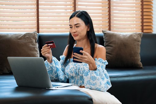 Young woman using online payment app and digital wallet on smartphone to pay with credit card. E commerce shopping and modern purchasing via mobile internet. Blithe