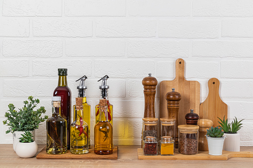 Stylish kitchen background with a set of bottles with various cooking oils, glass jars with spices, a set of kitchen tools. Front view