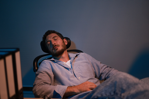 A young tired staff officer man using a desktop computer had overworked project overnight in the office exhausted unhappy businessman fell as sleepy  after working hard overtime at night