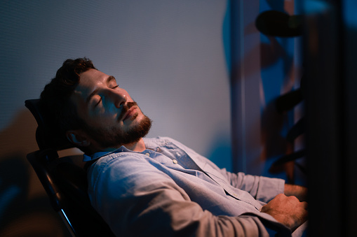 A young tired staff officer man using a desktop computer had overworked project overnight in the office exhausted unhappy businessman fell as sleepy  after working hard overtime at night