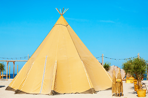 Large closed fabric tent on the sea beach. Tipi tent of nomadic American Indians on the beach.