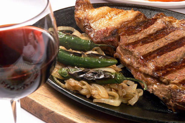 bife suculento cozido na grelha com cebola, pimentos serranos assados e copo de vinho tinto - fillet steak char grilled filet mignon steak - fotografias e filmes do acervo