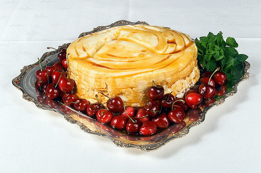 Pudding dessert with caramel sauce accompanied by natural cherries, caramel pudding, Neapolitan flan on a silver tray