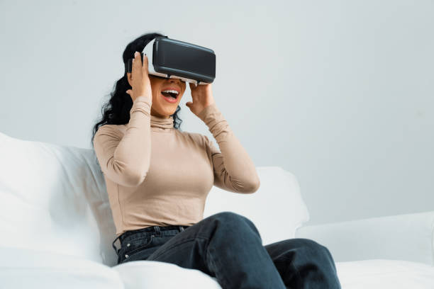 istock Young woman using virtual reality VR goggle at home for crucial experience 2053567289