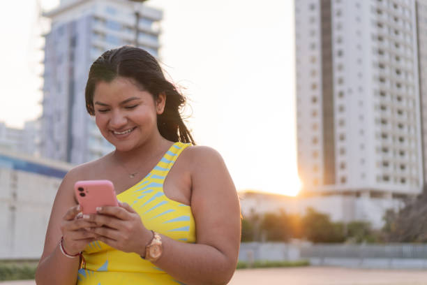 istock Content Woman Using Smartphone at Dusk in City 2053576450