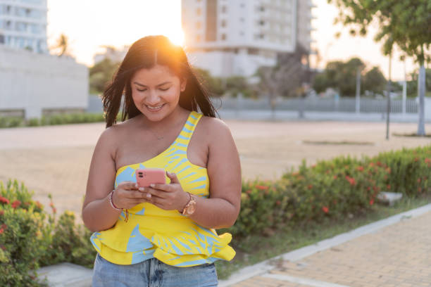 istock Joyful Woman Texting on Smartphone in Sunny Park 2053576460