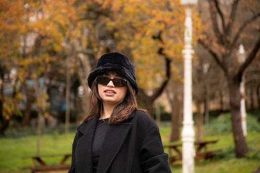 Portrait of a beautiful woman wearing a hat in a public park in autumn