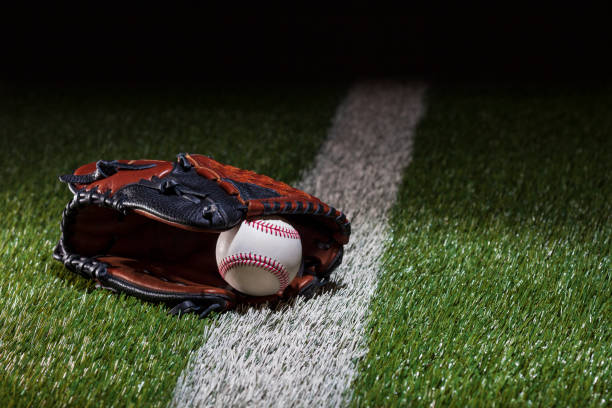 istock Baseball in a mitt at a low angle on a field with stripe and dramatic lighting and dark background 2053632068