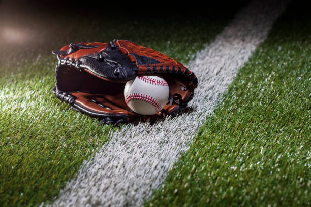 istock Baseball in a mitt at a low angle on a field with stripe and dramatic lighting and dark background 2053632070