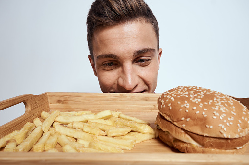 A man holds in front of him a pallet of fast food french fries hamburger lifestyle eating close-up. High quality photo