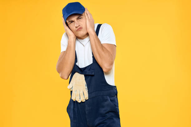 istock Working man in uniform of gloves rendering service yellow background 2053650522