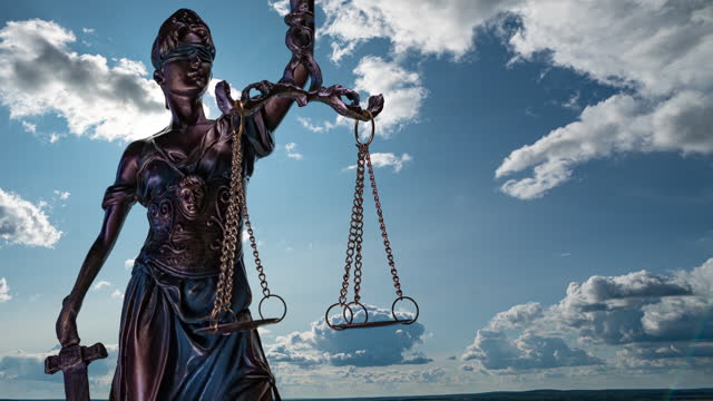 the statue of justice turns against the backdrop of clouds moving across the blue sky. time lapse 4k.