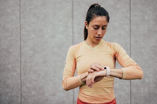 Young woman pauses to review her fitness tracker data after exercising. A moment of concentration and monitoring progress.