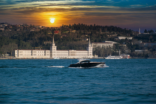 Power boat taxi in Bosphorus Strait moving fast and splashing water. Anatolian Site of Istanbul and Bosphorus Bridge in the background.
