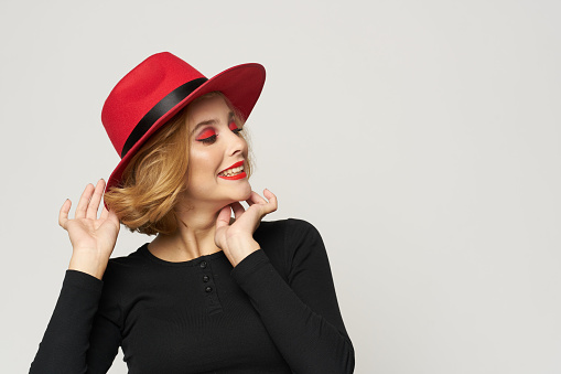 Fashionable woman in red hat black blouse red lips cropped view light background emotions. High quality photo