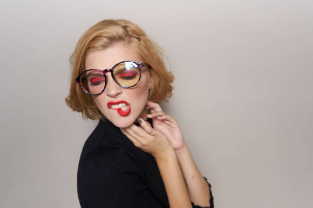 Blonde with short hairstyle with glasses red lips black jacket light background cropped view. High quality photo