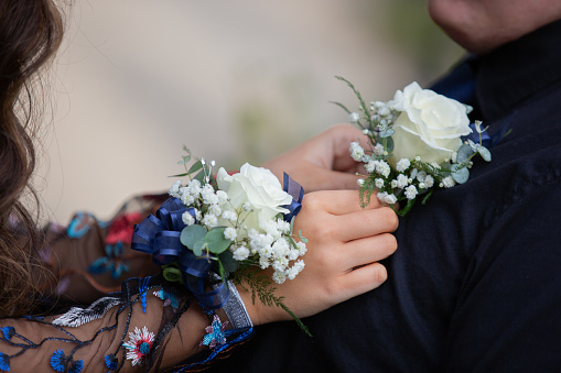 Young man and woman exchanging corsages prior to prom