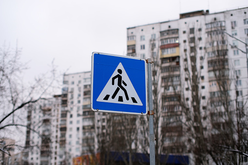 Pedestrian crossing sign against the background of city buildings. Safety sign.