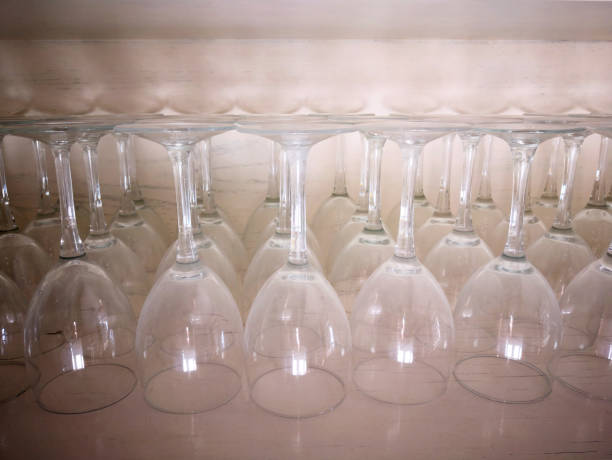 istock Many empty shiny transparent upturned (overturned, inverted) clean water or wine glasses of classic form put in rows upside down in an old wooden cupboard in small village restaurant, prepared for serving the clients 2053790193