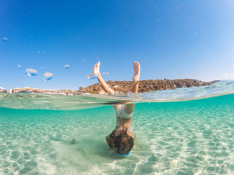 Girl having so much fun diving underwater in a crystal clear sea water on her summer vacation
