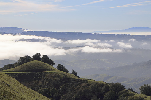 The hills and mountains of Las Trampas Wilderness enjoy the morning sun while morning fog obscures the sun in the valley below