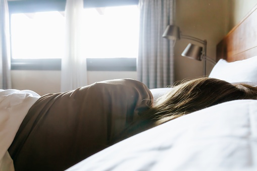 Back shot of a young woman with long hair lying in bed while sleeping. Horizontal with copy space.
