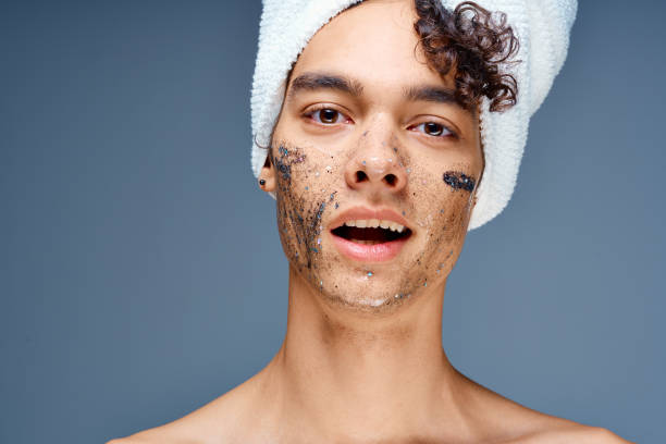 istock Cheerful guy with bare shoulders with a towel on his head, a black mask on his face 2053866160