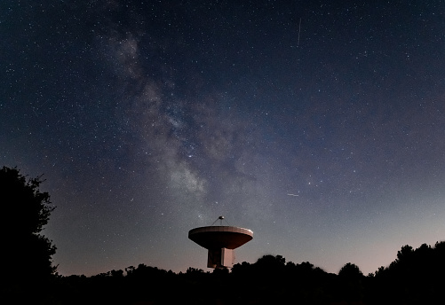 Giant space observatory with a milky way in the background next to a starry sky
