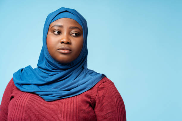 portret poważna muzułmanka ubrana w tradycyjny hidżab na białym tle na niebieskim tle, kopia przestrzeni - chusta zdjęcia i obrazy z banku zdjęć